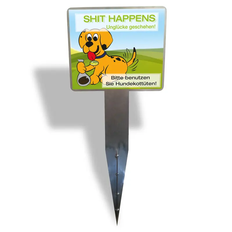 Hinweisschild mit Cartoon-Hund und Aufschrift „Shit Happens – Bitte benutzen Sie Hundekottüten!“ auf einem Erdspieß zur Bodenverankerung